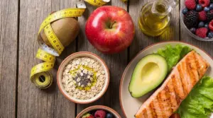 Alimenti salutari come salmone, avocado, avena, frutti di bosco, mela e olio d'oliva per abbassare il colesterolo