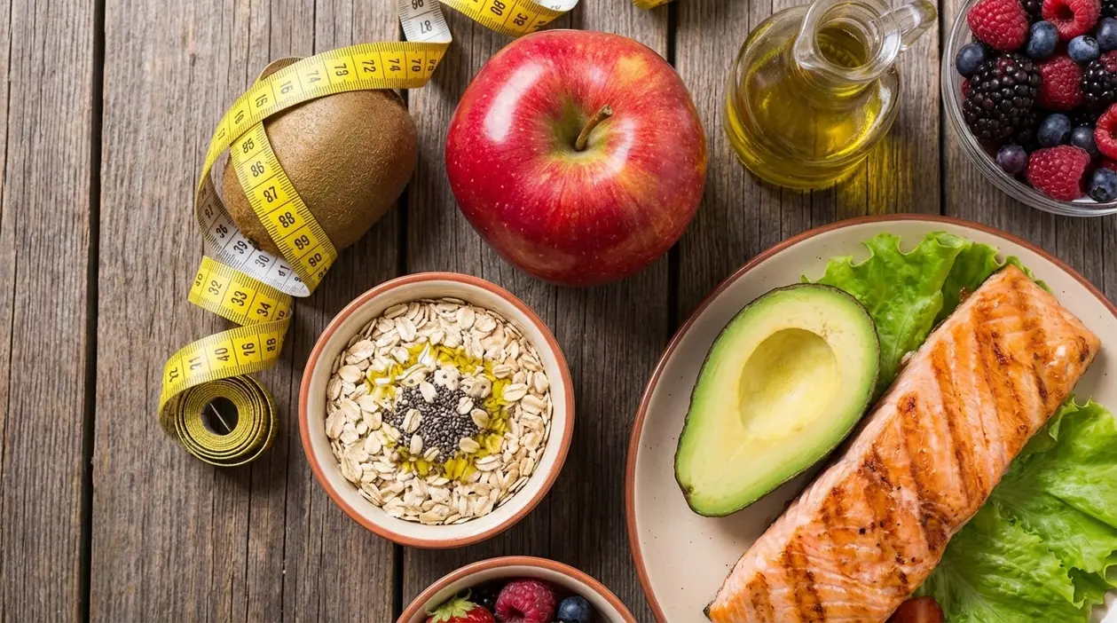 Alimenti salutari come salmone, avocado, avena, frutti di bosco, mela e olio d'oliva per abbassare il colesterolo