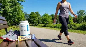 Donna che cammina in un parco con panchina, scarpe sportive e borraccia, in un contesto legato a dimagrimento e camminata