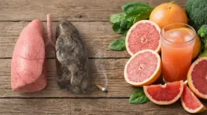 Polmoni sani e danneggiati accanto a pompelmo, succo agrumato e verdure su un tavolo di legno