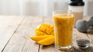 Frullato di mango e semi di chia in un bicchiere, con mango fresco, shaker e pesi sul tavolo