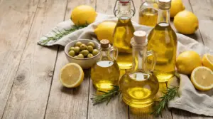 Bottiglie di olio di oliva con limoni freschi, olive verdi e rosmarino su tavolo di legno