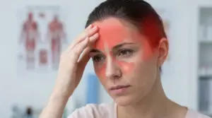 Donna con la mano sulla fronte e rossore sul viso, segno di dolore alla testa e ai seni nasali