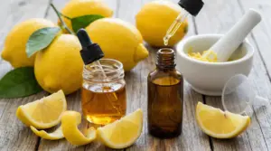 Limoni e flaconi con contagocce per olio essenziale di limone su tavolo in legno, con scorza e mortaio